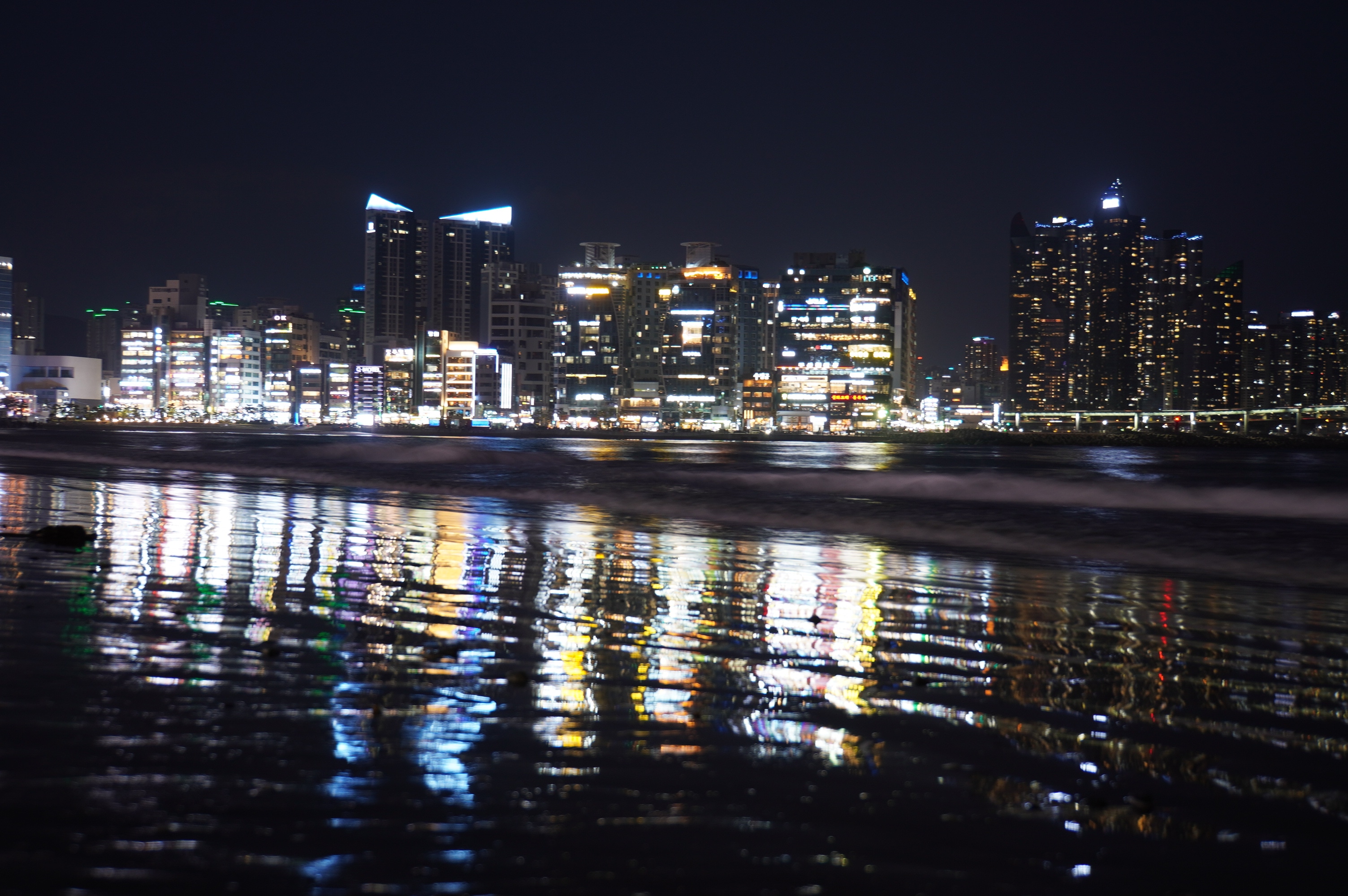 Blick auf Strand und hell leuchtende Stadt